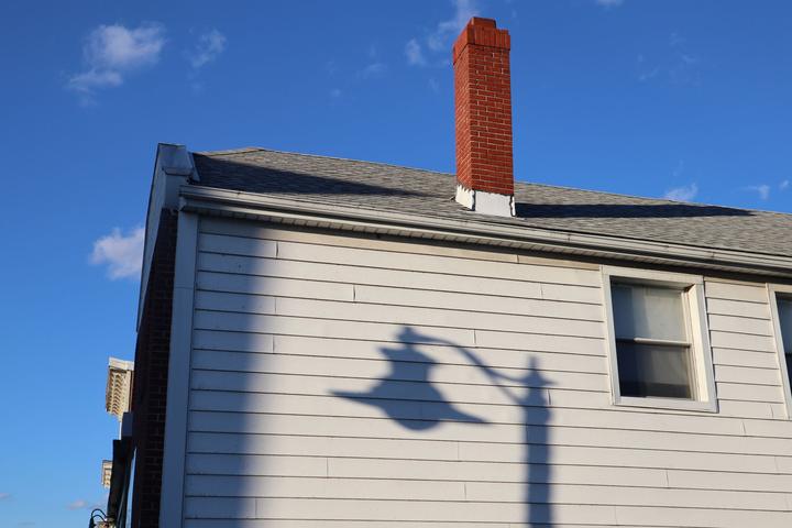 Brick chimney above the roof of a light-sided house